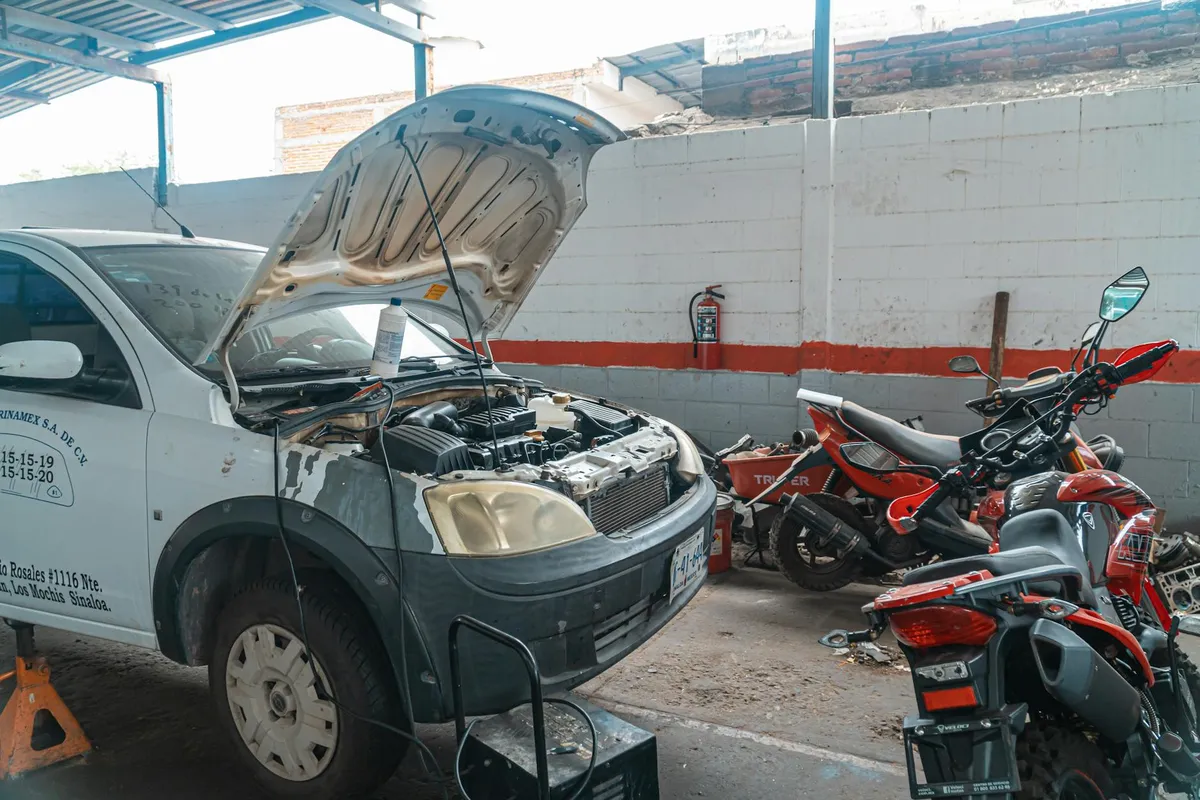 Samochód naprawiany w garażu z motocyklami i narzędziami wokół