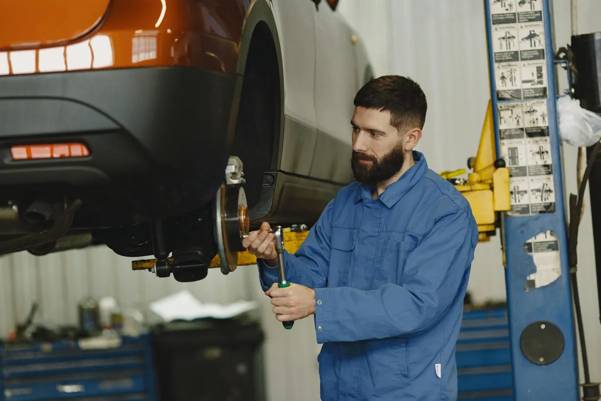 Zawodowy mechanik pracujący nad serwisem samochodu w warsztacie samochodowym
