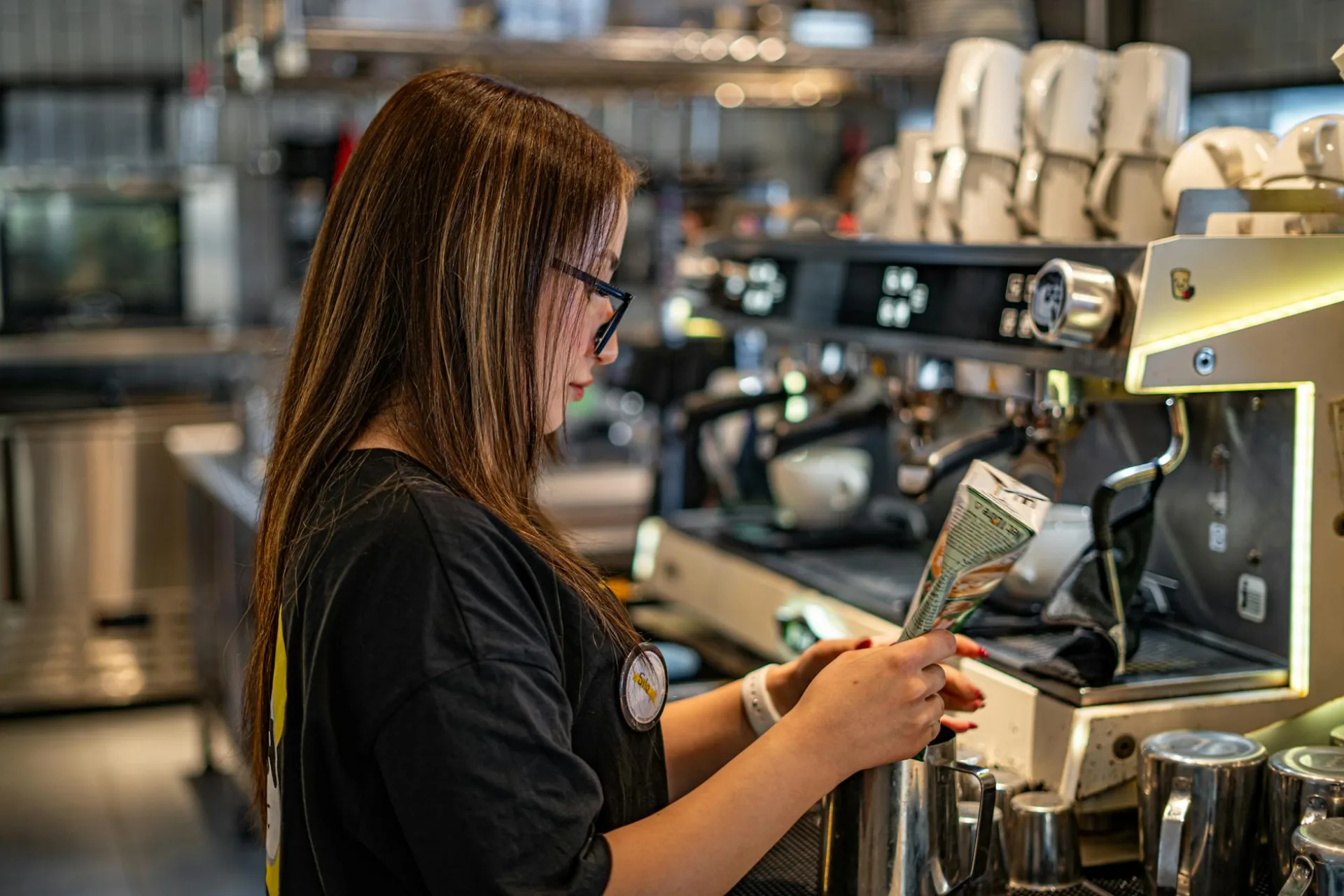 Młoda barista robiąca kawę przy ekspresie do kawy w modnej kawiarni