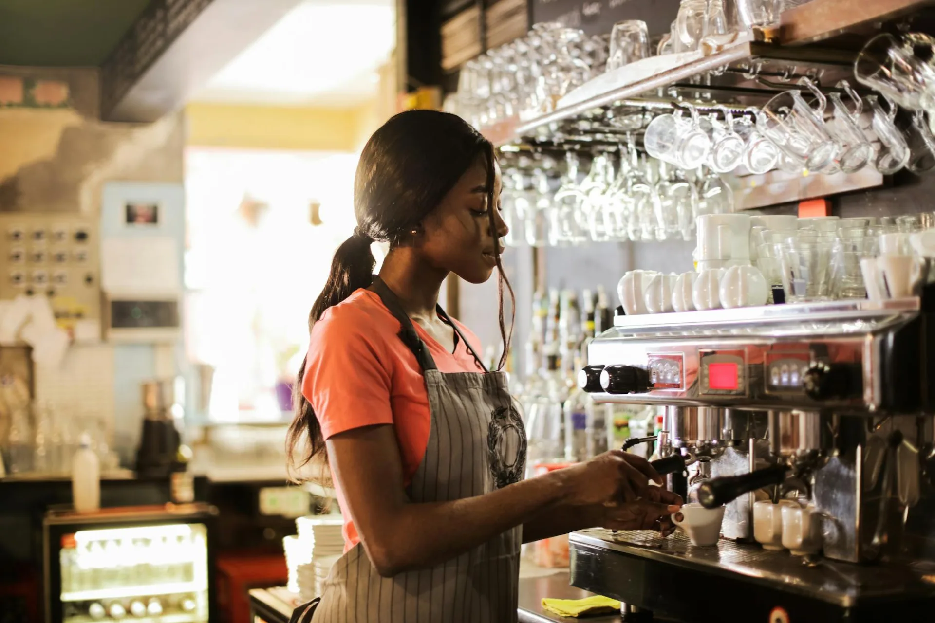 Barista robiąca espresso w stylowej kawiarni z nowoczesnymi maszynami do kawy i szklarnią
