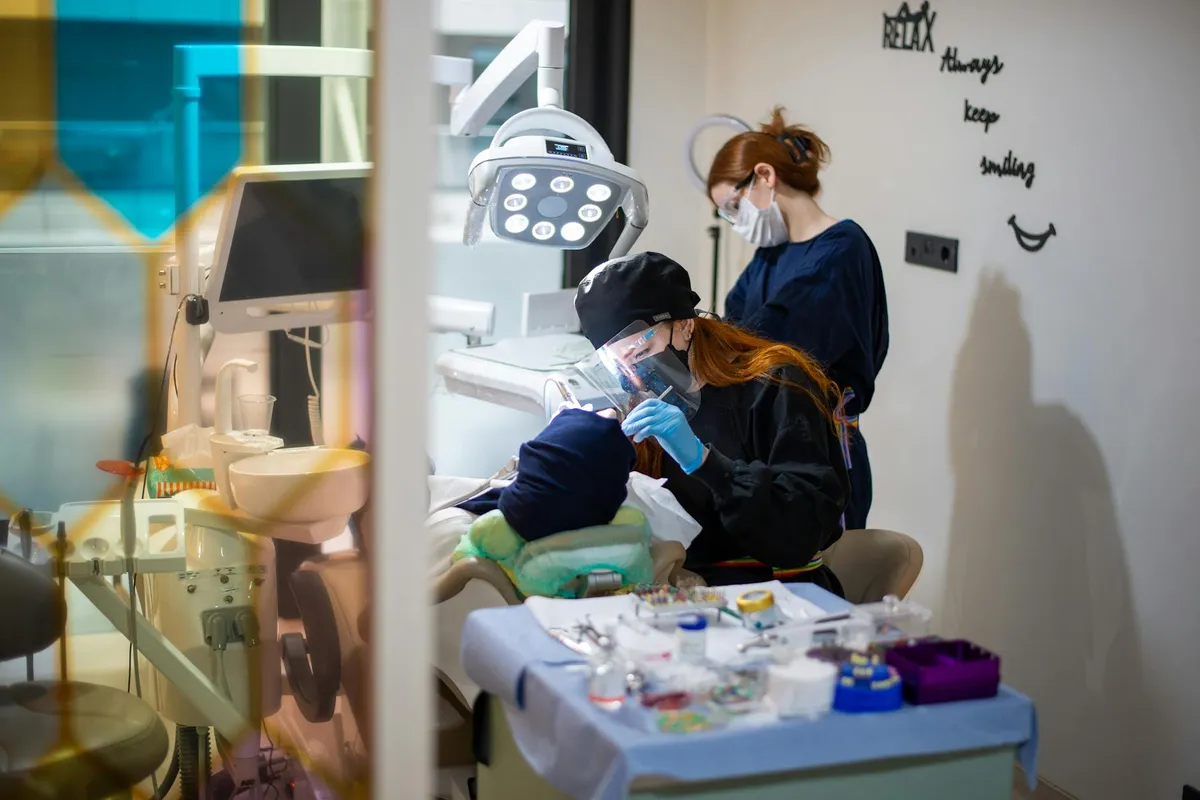 Dentysta wykonuje procedurę z zaawansowanym sprzętem podczas gdy asystent się przygotowuje