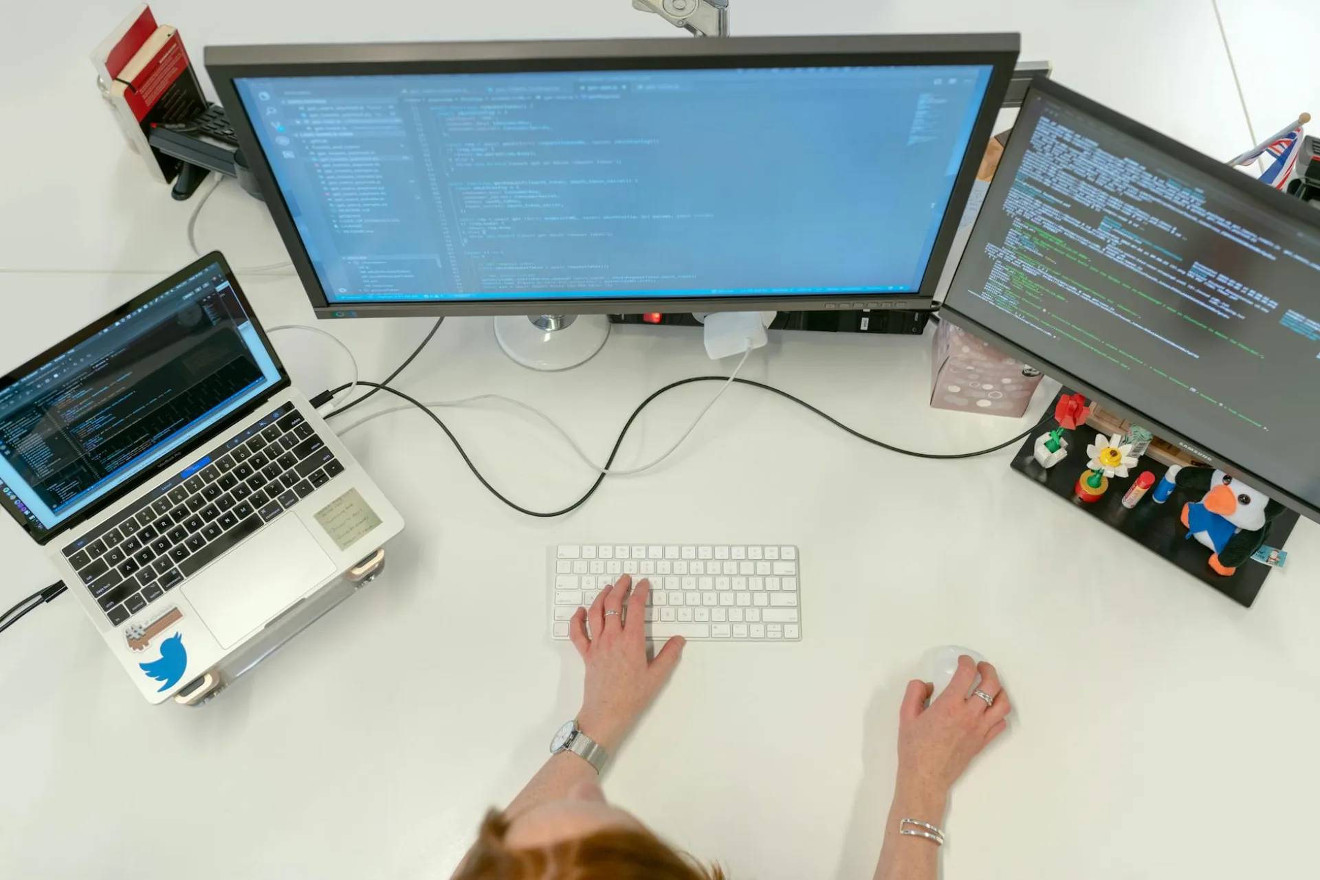 Kobieta inżyniera oprogramowania kodująca na dwóch monitorach i laptopie w biurze