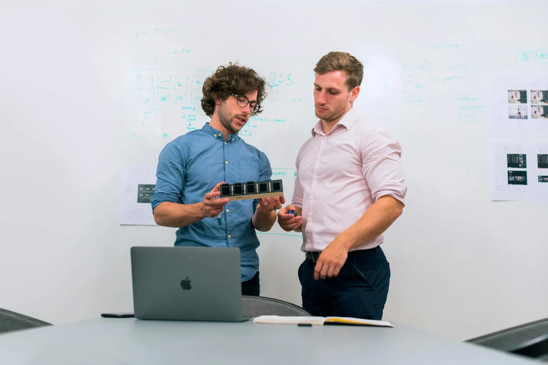 Dwaj mężczyźni w biurze omawiają i sprawdzają prototyp techniczny