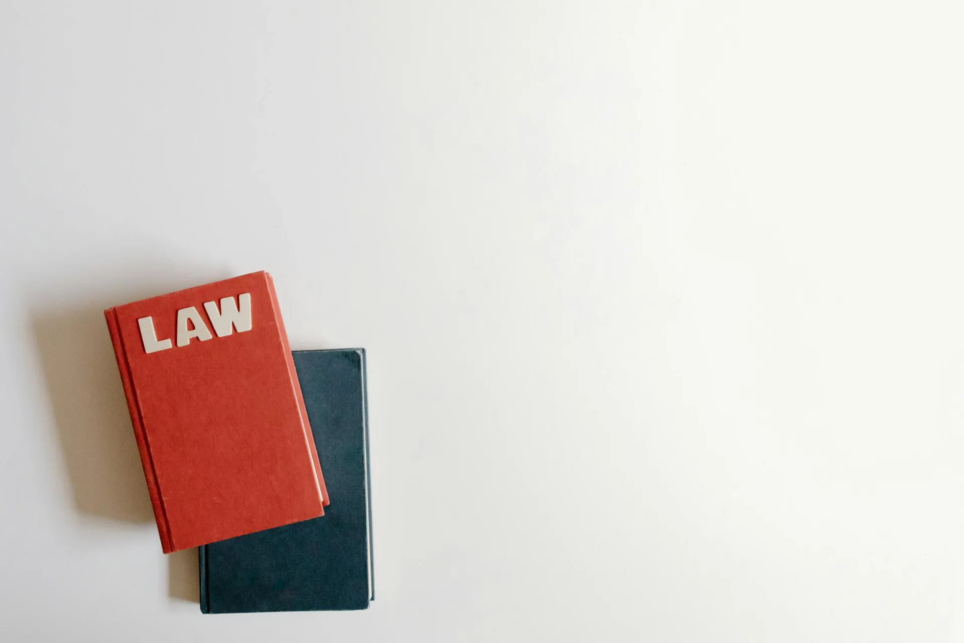 Kolażowy układ: czerwona książka prawa i niebieska książka na białym tle, idealne do tematów prawnych