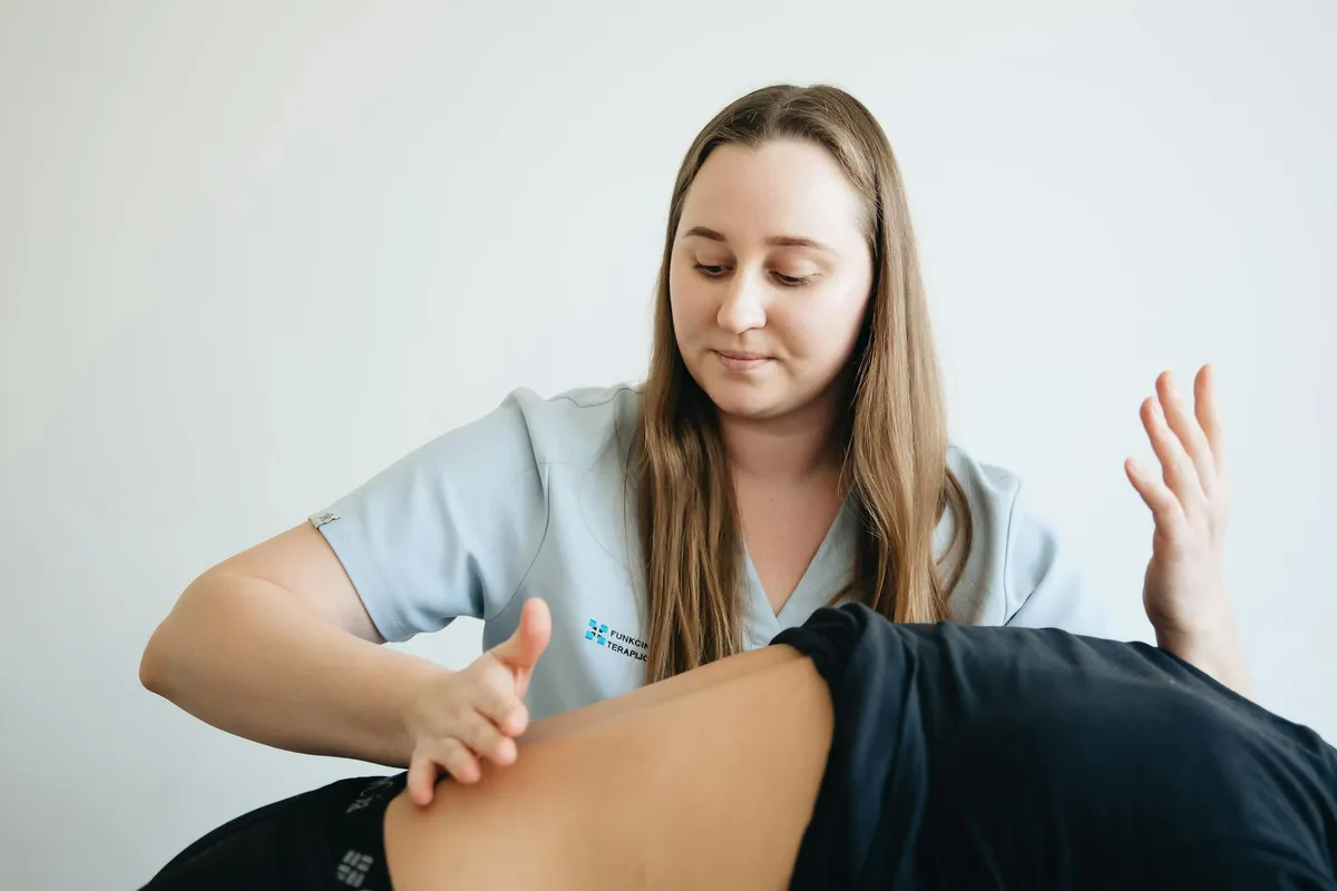 Kobieta fizjoterapeutka udzielająca masażu terapeutycznego pacjentowi w klinice