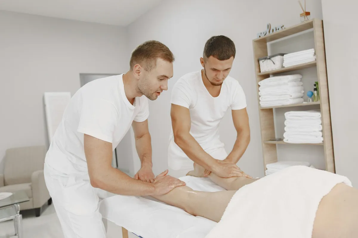 Dwaj terapeuci męscy udzielający masażu nogi w spokojnym środowisku spa
