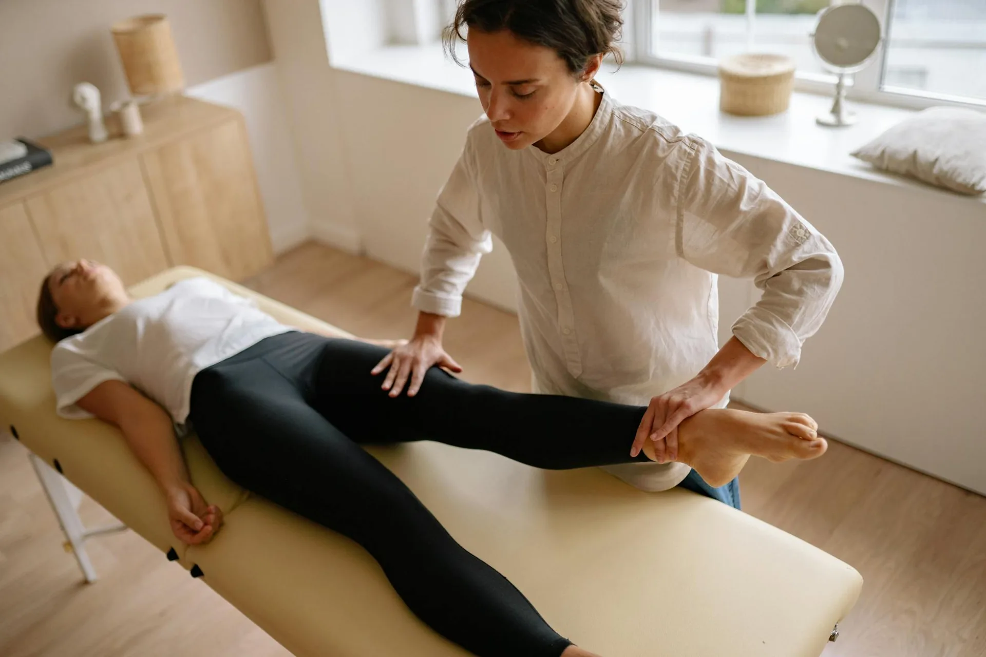 Fizjoterapeuta wspomaga kobietę terapią rehabilitacyjną nóg w spokojnym pokoju zabiegów